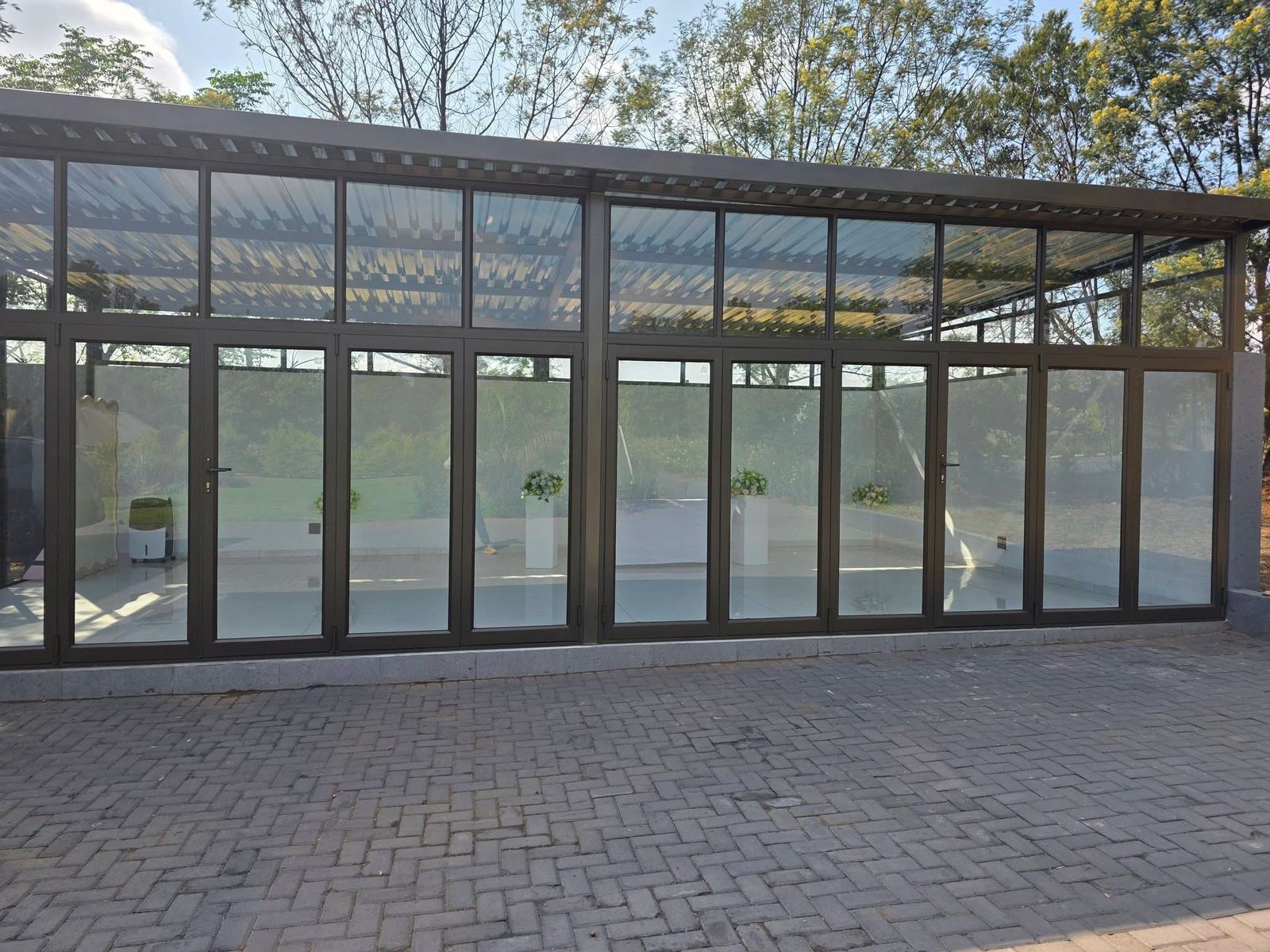 Tshedza Venue, a glass-walled venue with a paved patio at Muano Functions Venue